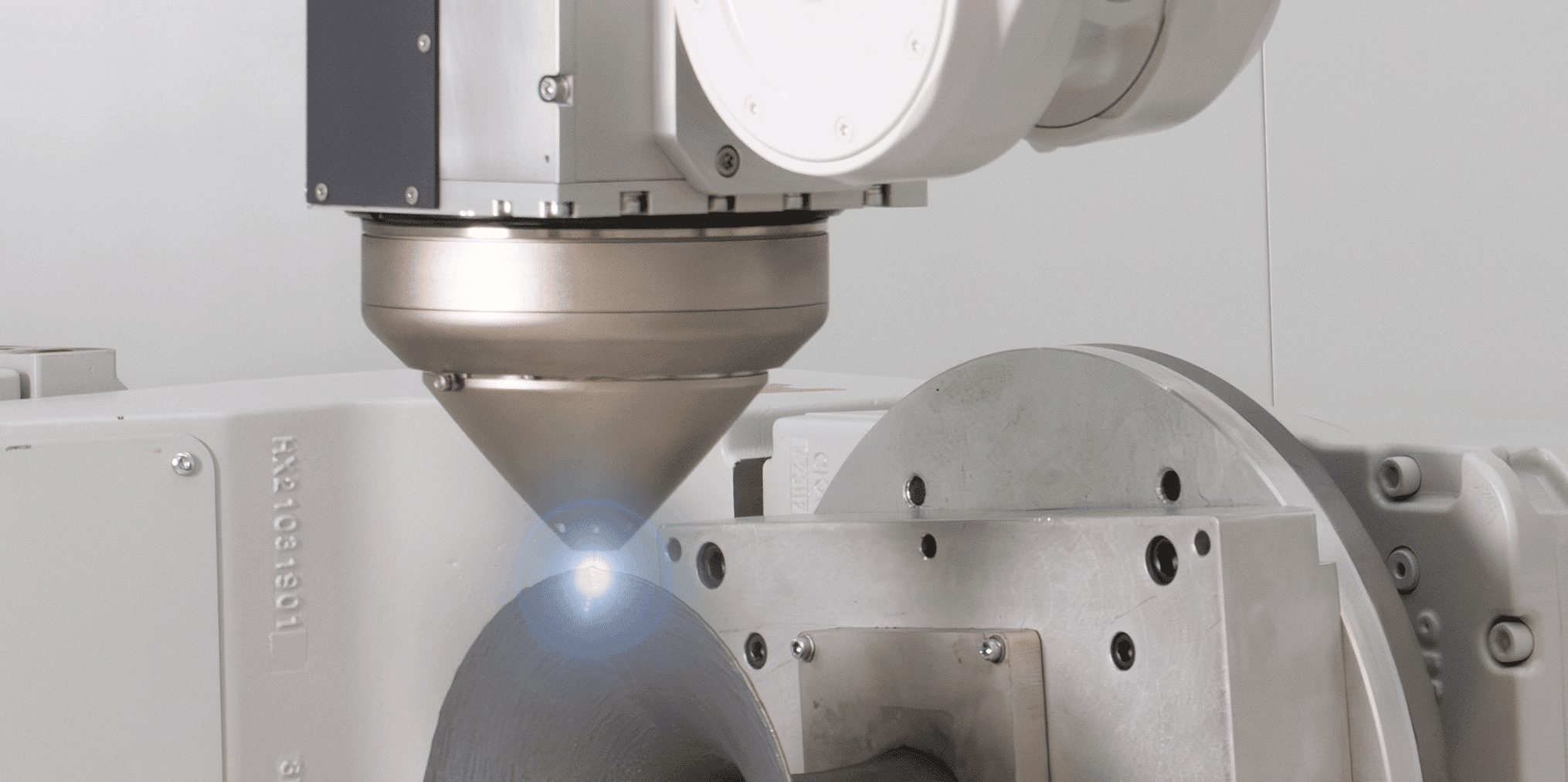 Meltio print head on an industrial robot printing onto a part on the positioner